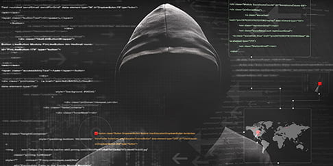 An anonymous hacker in a dark hooded sweatshirt stands behind a wall of digital code.