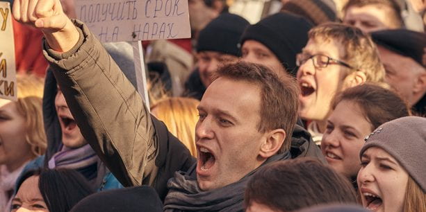 Russian opposition leader Alexei Navalny shouts in the middle of a crowd of protestors with his fist in the air.